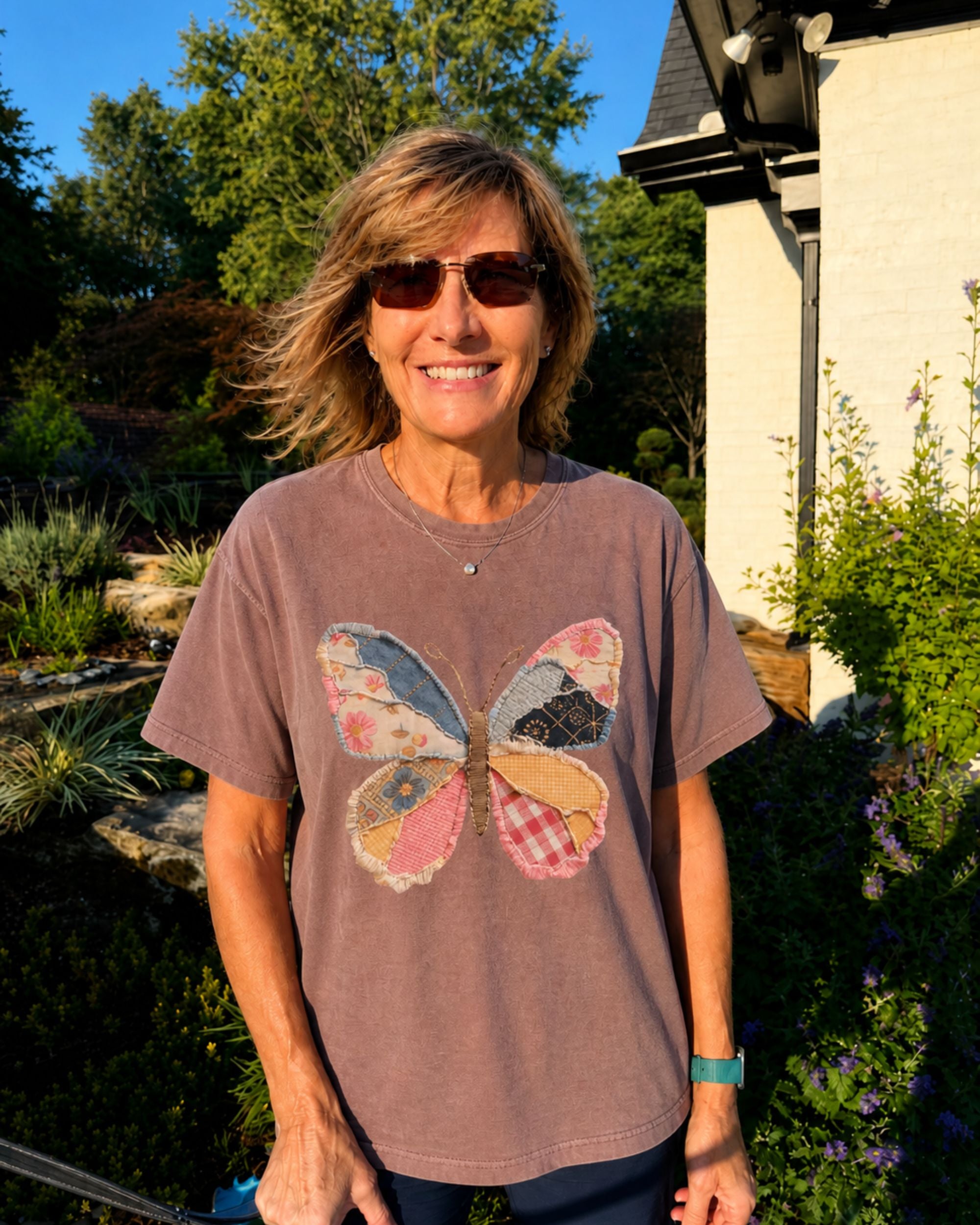 Woman wearing a brown t-shirt with a butterfly design outdoors.