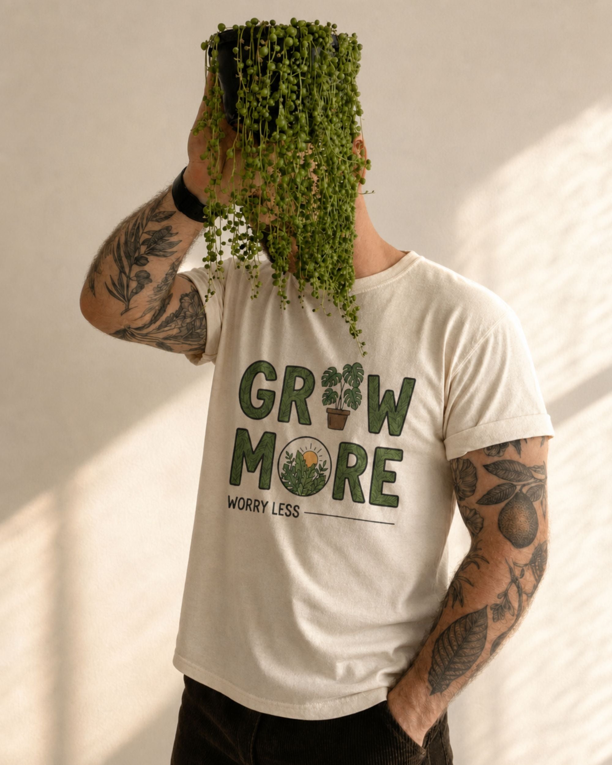 Person wearing a white t-shirt with 'Grow More Worry Less' text, holding a potted plant.